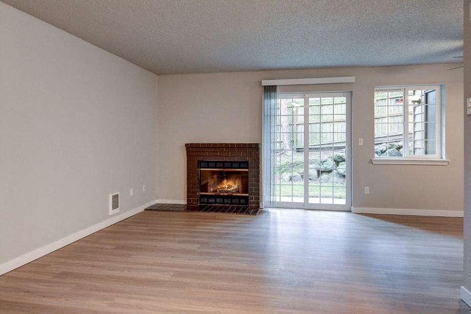 an empty living room with a fireplace and a glass door