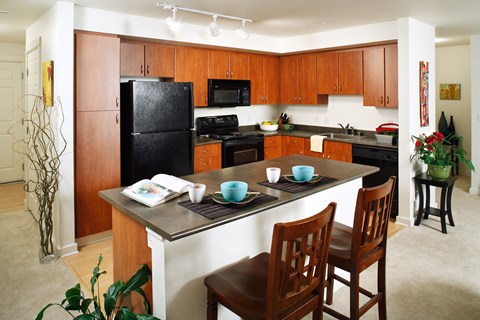 a kitchen with black appliances and a counter with chairs