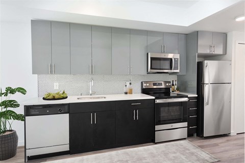 a kitchen with black and white cabinets and stainless steel appliances