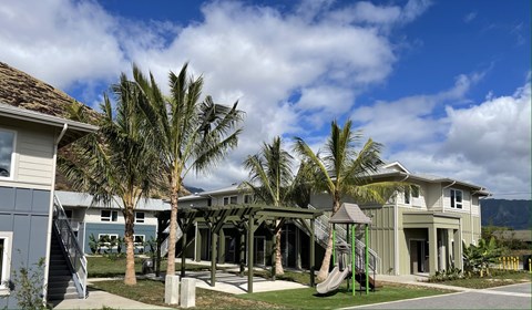 A playground area is located in front of a two-story house.