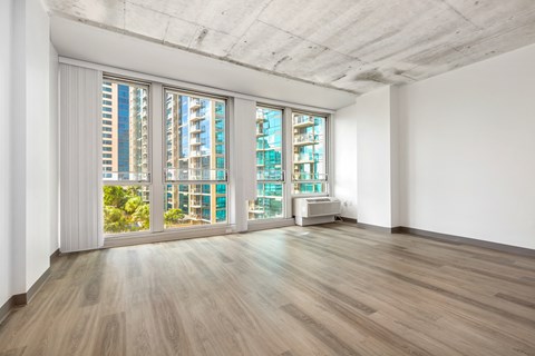 an empty living room with wood floors and a large window
