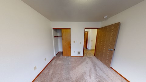 a living room with a carpeted floor and a door to a hallway