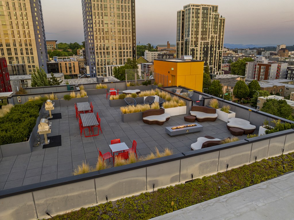 a roof deck with lounge furniture and a yellow building in the background