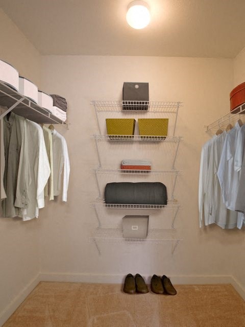 a closet with a rack of clothes and some shoes