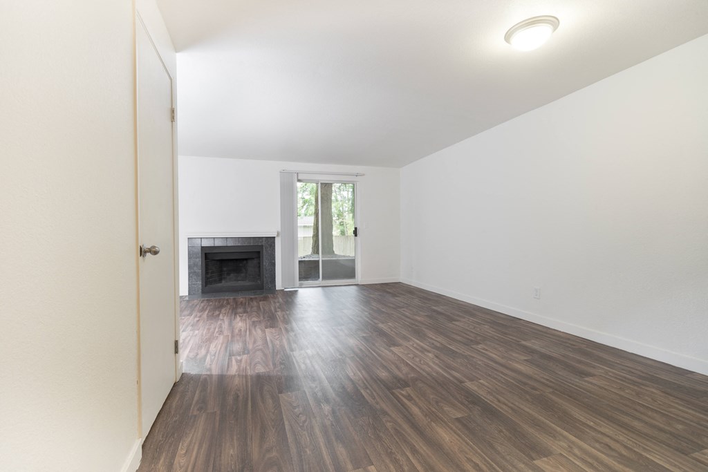 an empty living room with hard wood floors and a fireplace