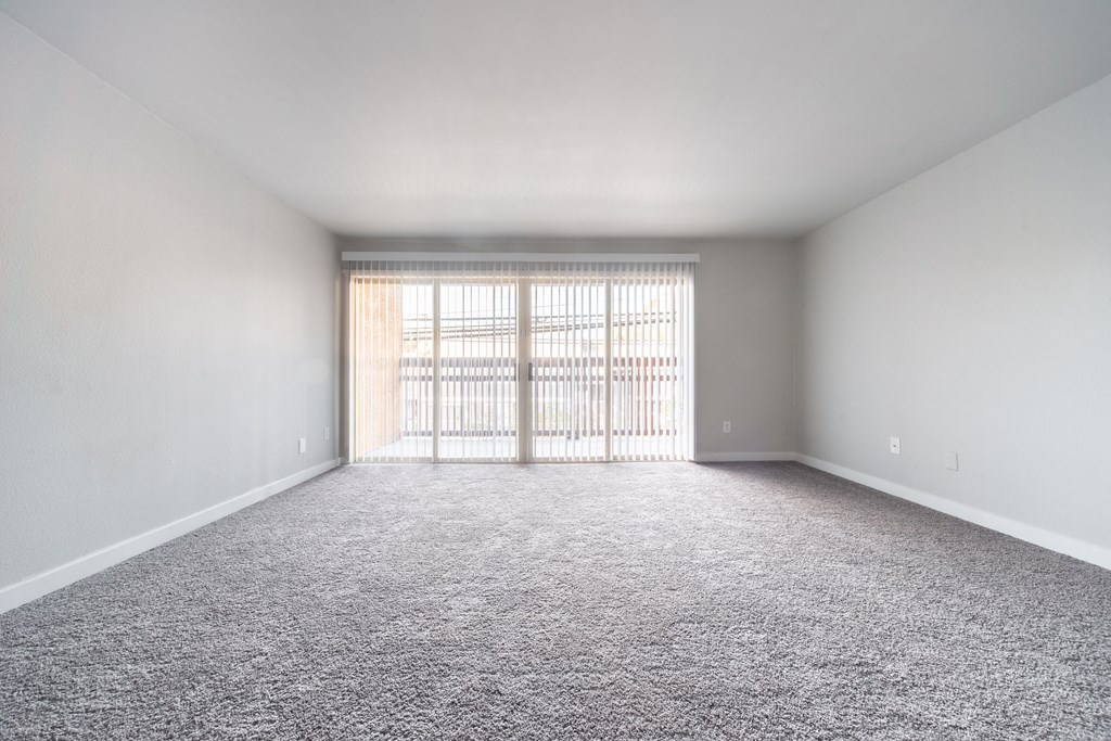 an empty living room with a window and carpet