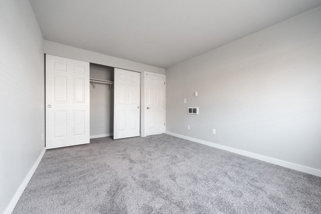 a room with carpet and white doors and a closet