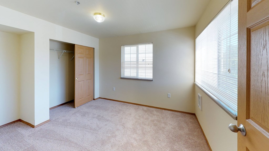 an empty bedroom with a closet and a window