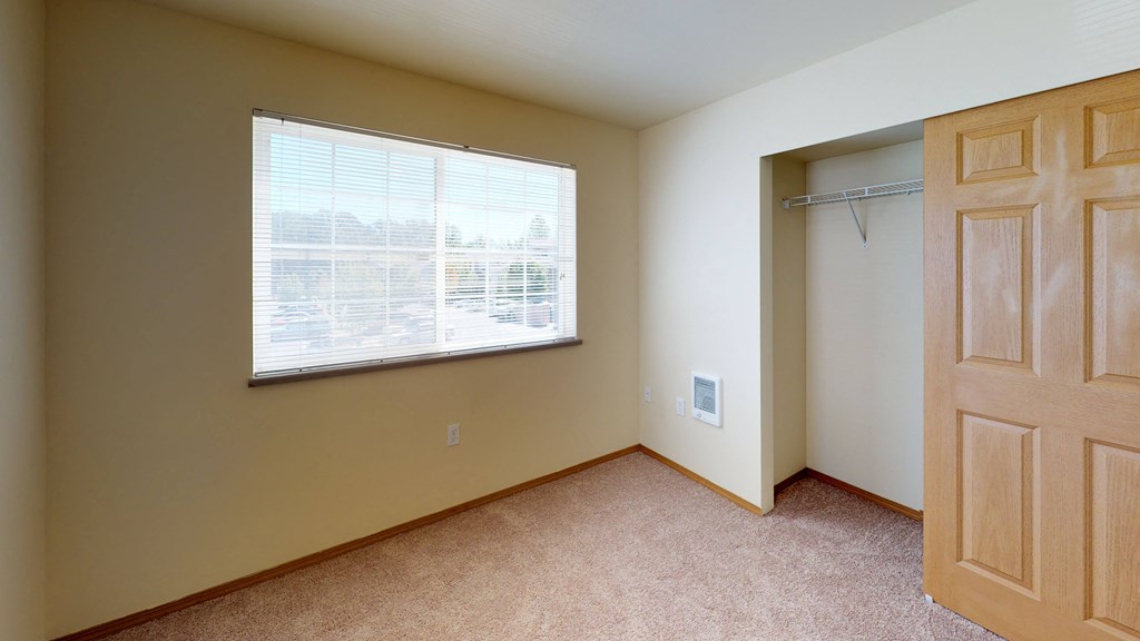 an empty bedroom with a large window and a closet