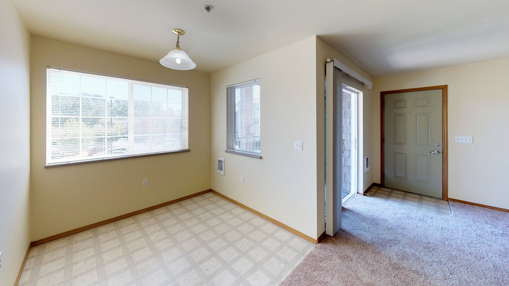 an empty living room with a large window and a door to a hallway