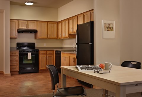 A kitchen with a black refrigerator and wooden cabinets.