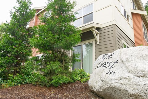 A large rock with the words "Cob West 341" written on it in front of a house.
