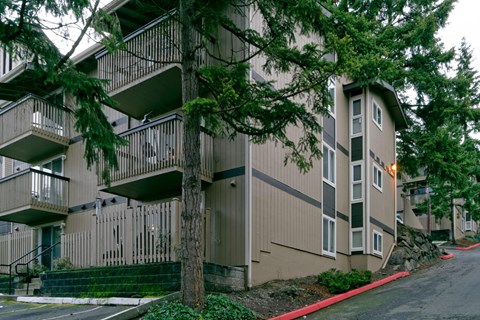 Apartment building with balconies and trees in front.