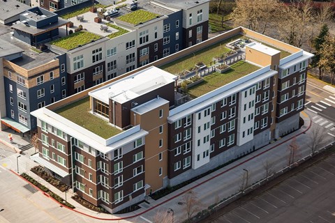 A large building with a green roof is surrounded by a parking lot.