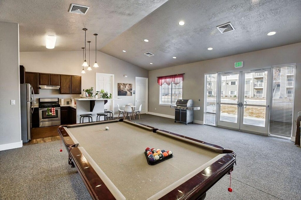 a game room with a pool table and a kitchen