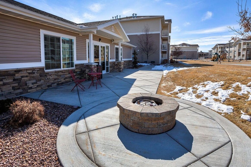 a paved patio with a fire pit in front of a house