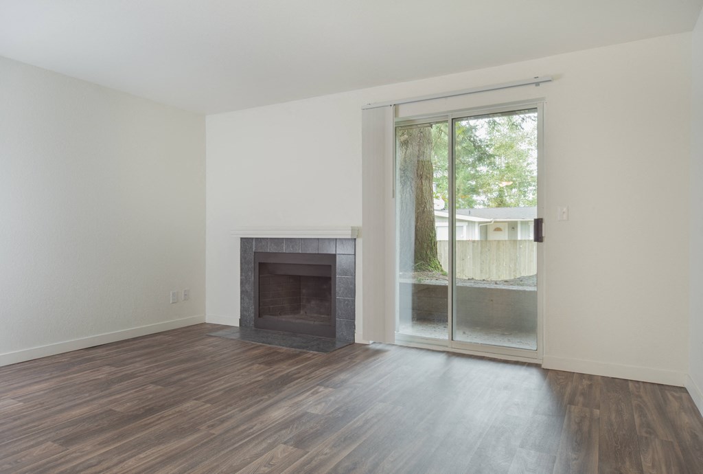 an empty living room with a fireplace and a sliding glass door