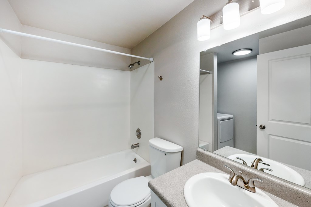 A white bathroom with a toilet, sink, and bathtub.
