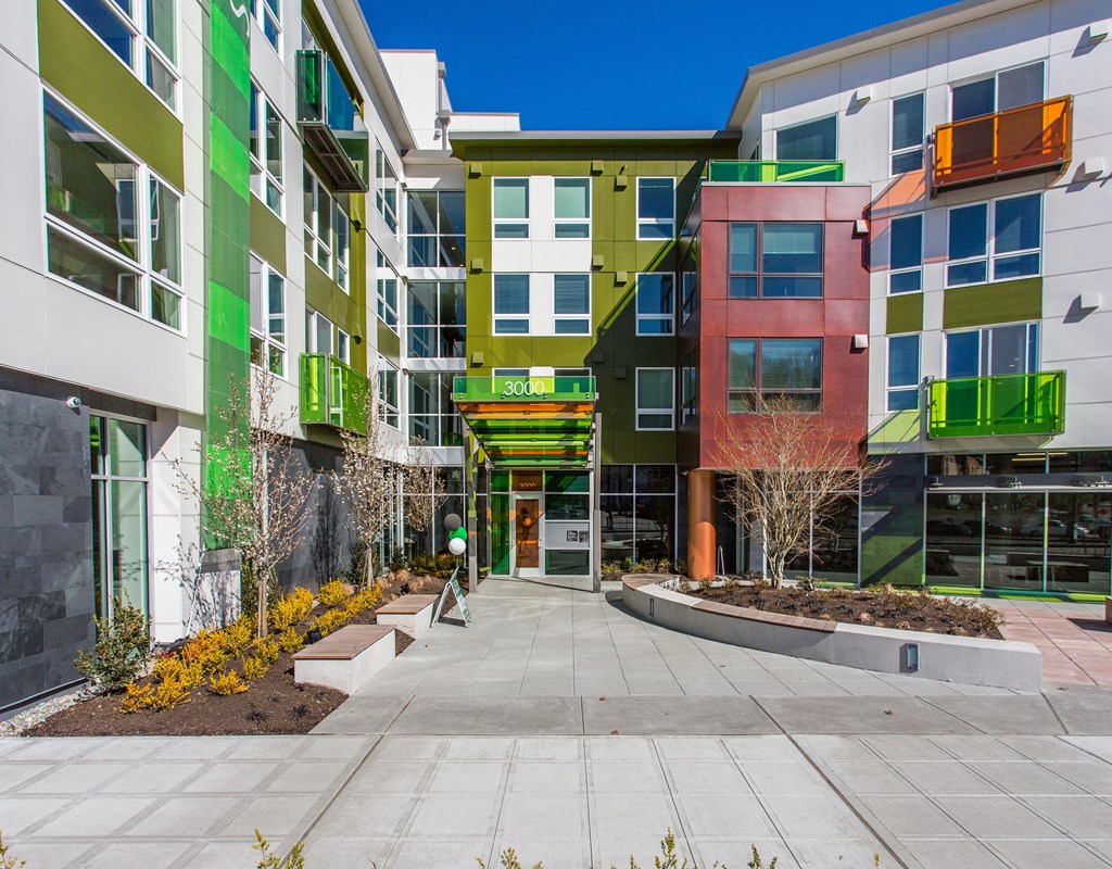 an exterior view of an apartment complex with colorful buildings and a sidewalk