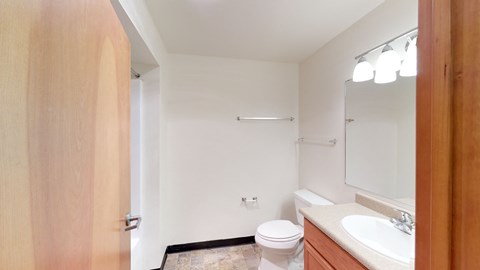 A bathroom with a toilet, sink, and mirror.