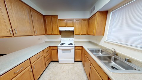 A kitchen with wooden cabinets and a white stove top oven.
