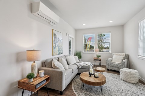 A well-lit living room with a couch, coffee table, and a painting on the wall.
