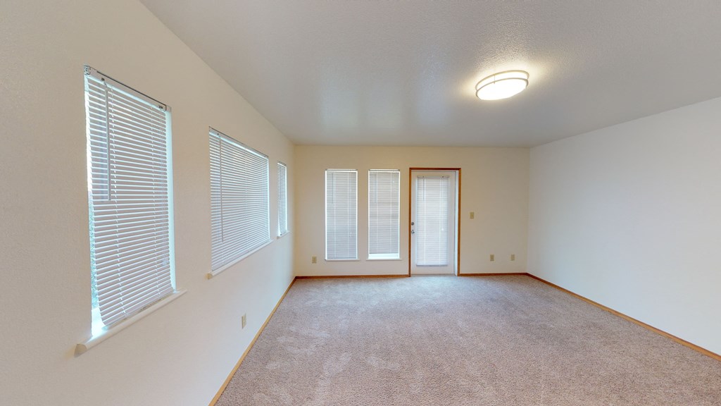 an empty living room with windows and a door