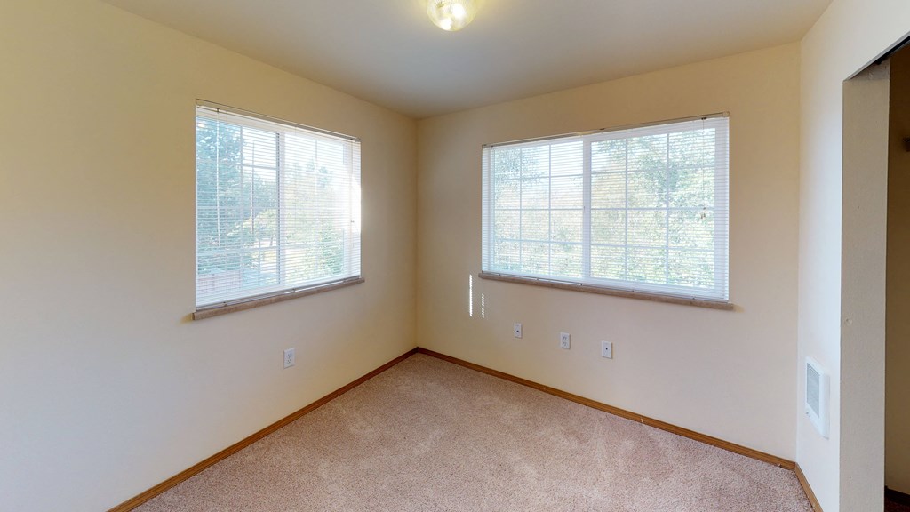 the living room of a home with two windows and carpeting