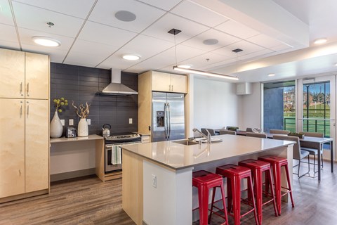 a kitchen with an island and red bar stools in front of a dining room