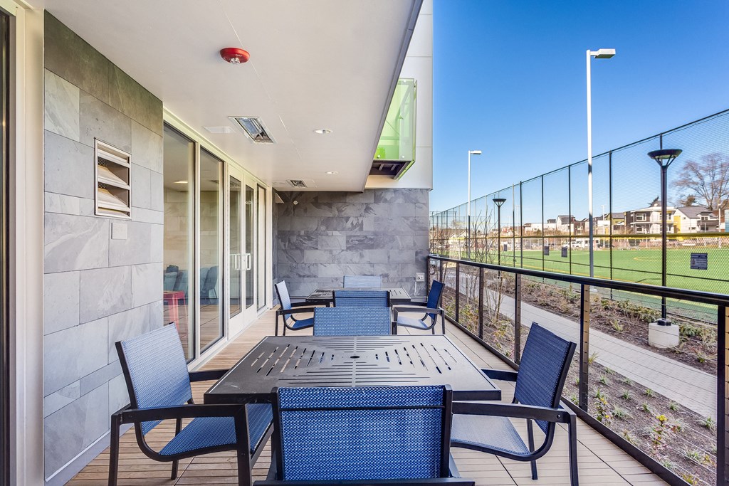 a patio with tables and chairs and a view of a soccer field