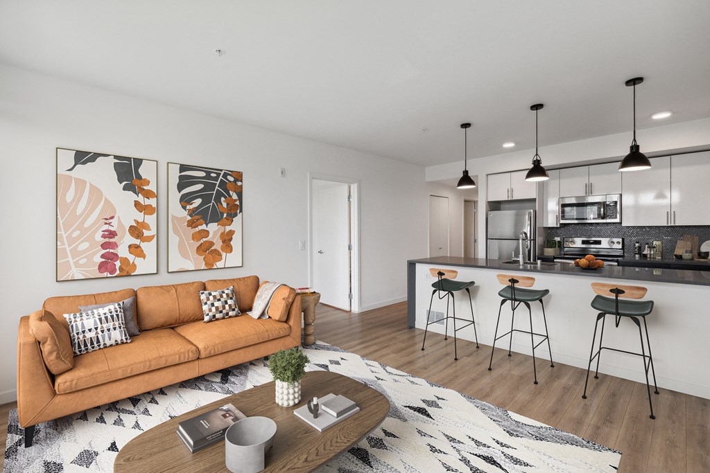 a living area with a couch coffee table and a kitchen with a breakfast bar