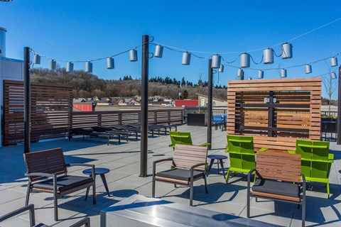 the patio on the roof of the building has chairs and tables