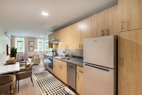 A modern kitchen with wooden cabinets and a black and white checkered rug.