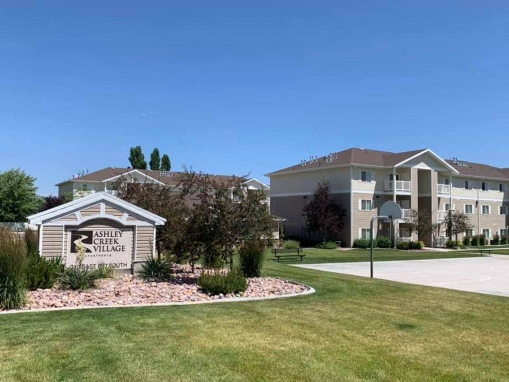 an exterior view of an apartment building with a sign on the side of a driveway