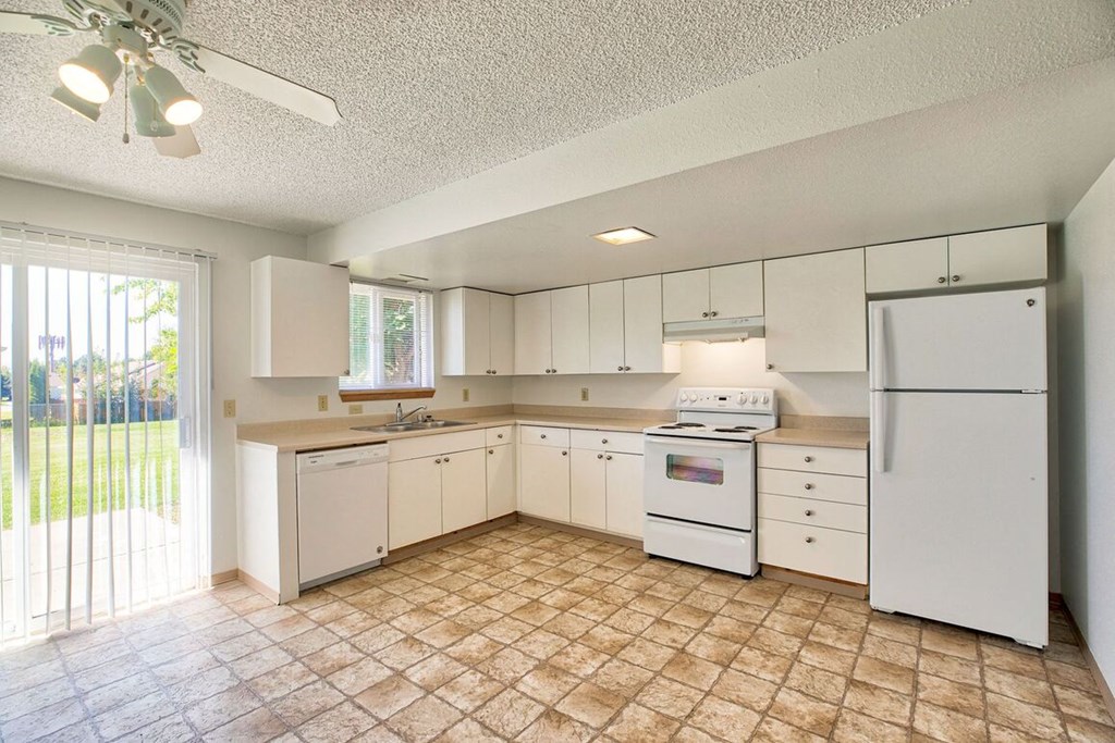 a kitchen with white appliances and a sliding glass door