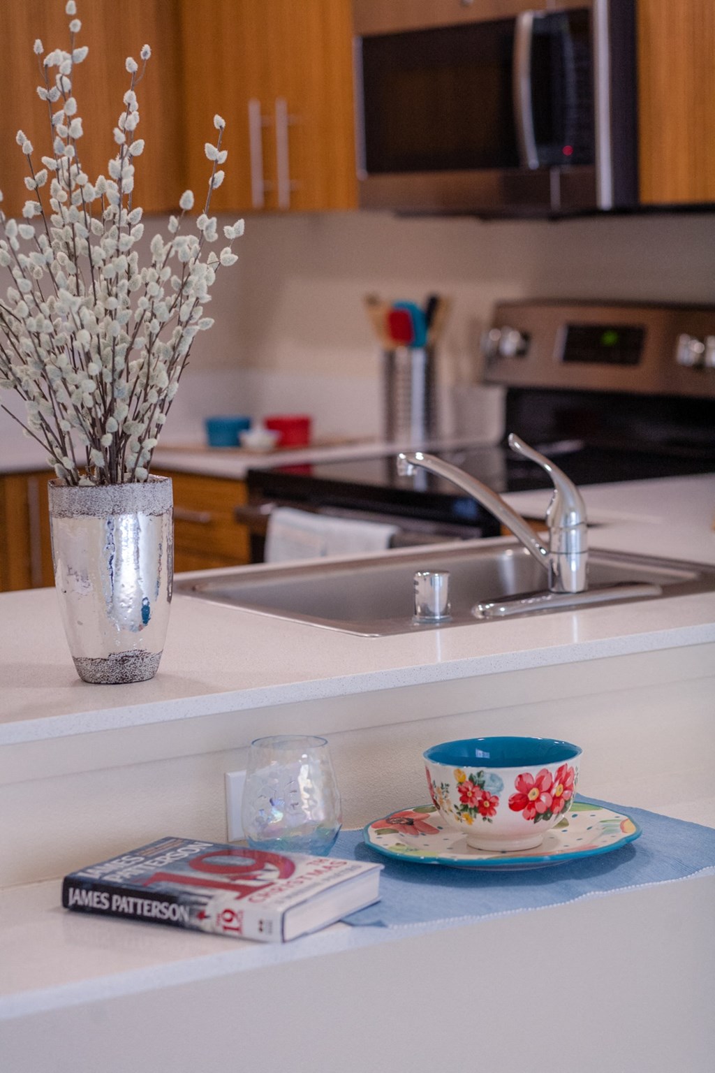a kitchen counter with a sink and a cup and a vase with flowers