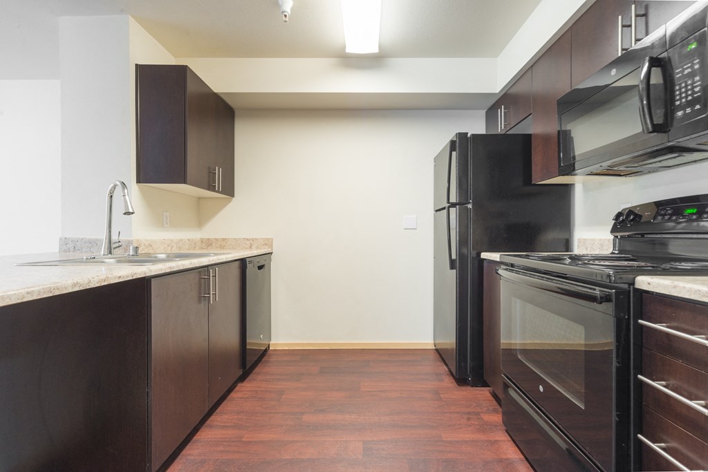 a kitchen with dark wood cabinets and stainless steel appliances