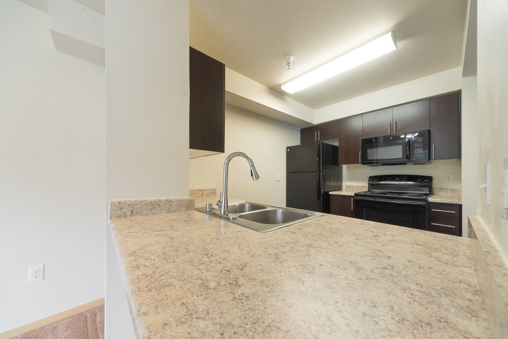a kitchen with granite countertops and black appliances
