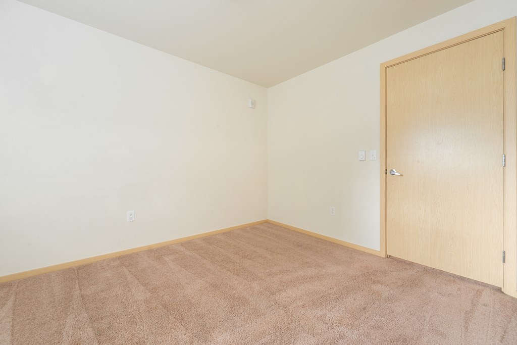 a bedroom with a carpeted floor and a wooden door