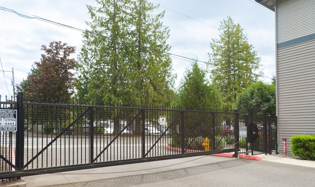 a gate to a parking lot with trees in the background