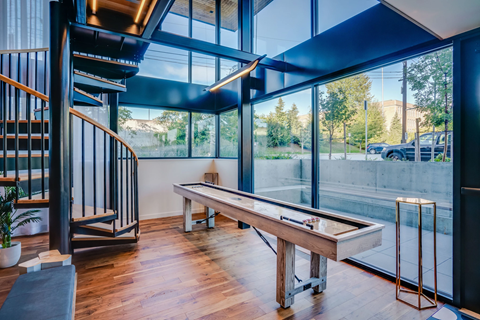 a pool table in a room with glass walls and a staircase