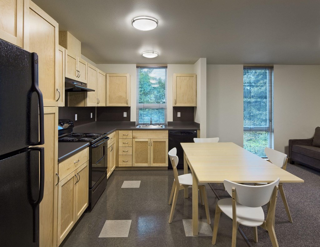 A kitchen with a black refrigerator and wooden cabinets.