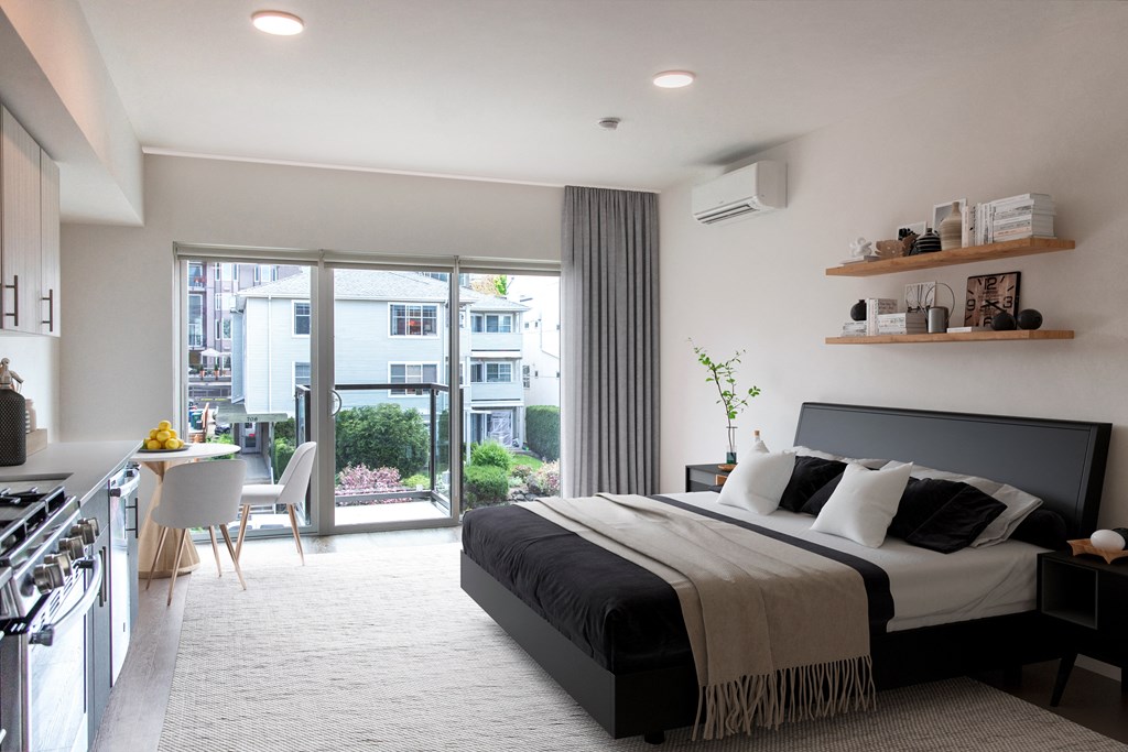 a bedroom with a bed and a kitchen and a balcony