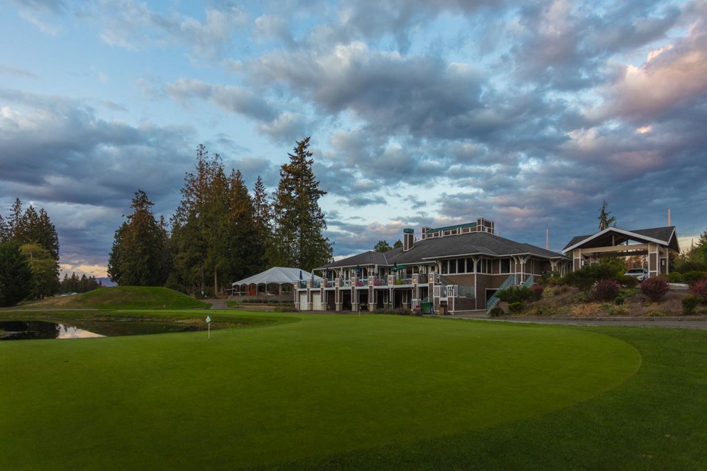 a golf course with a building in the background and a cloudy sky