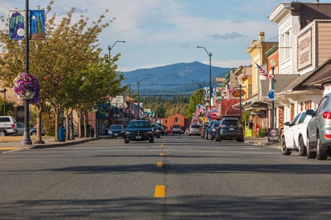 a city street with cars and buildings and mountains in the background