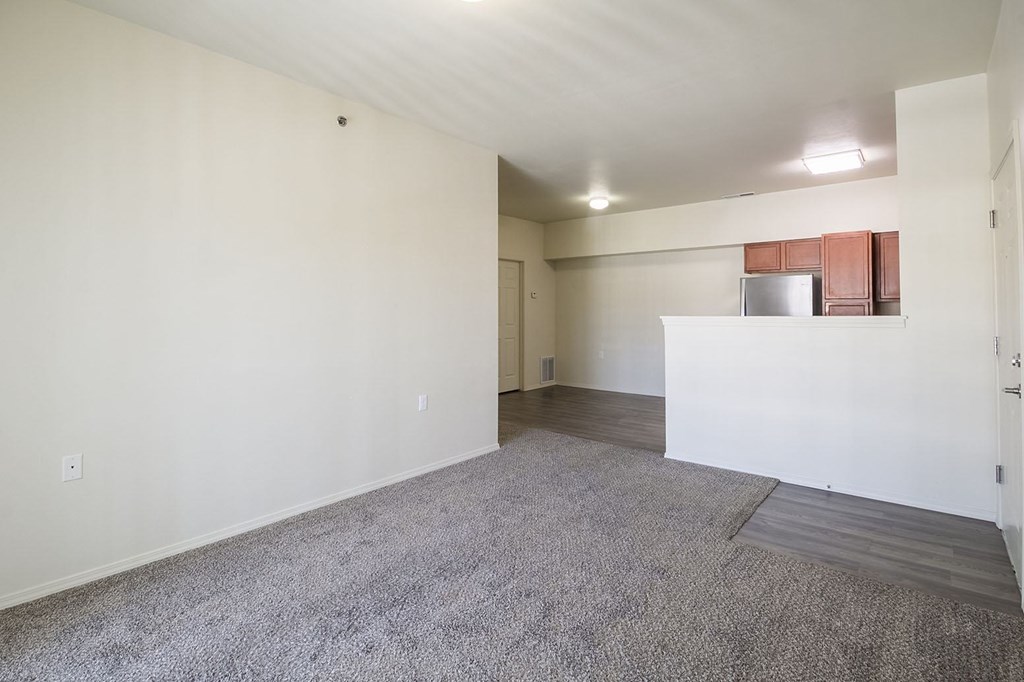 A large, empty room with a carpeted floor and white walls.