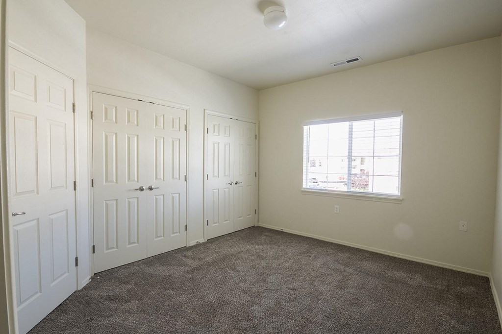 A room with white doors and a window with a view of a city.