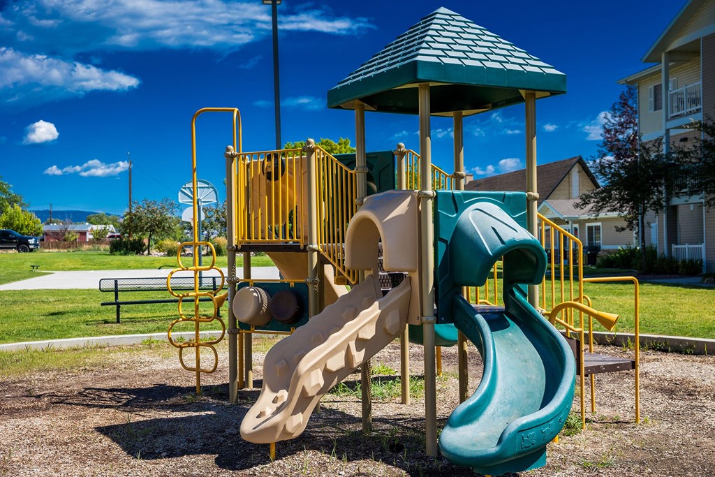 A playground with a green slide and a yellow structure.