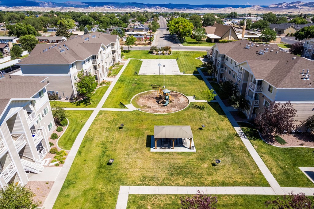 A large grassy area with a pavilion in the middle of apartment buildings.