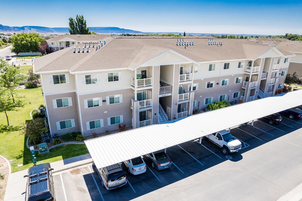 A large apartment complex with a parking lot in front.